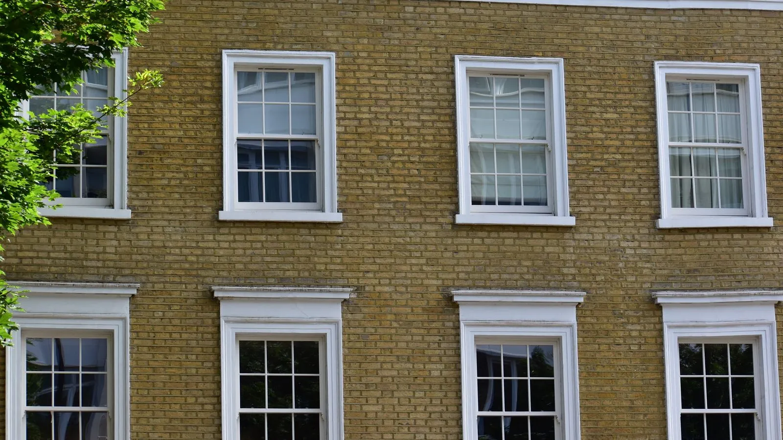 Brick building with traditional white sash windows, candidates for retrofit double glazing