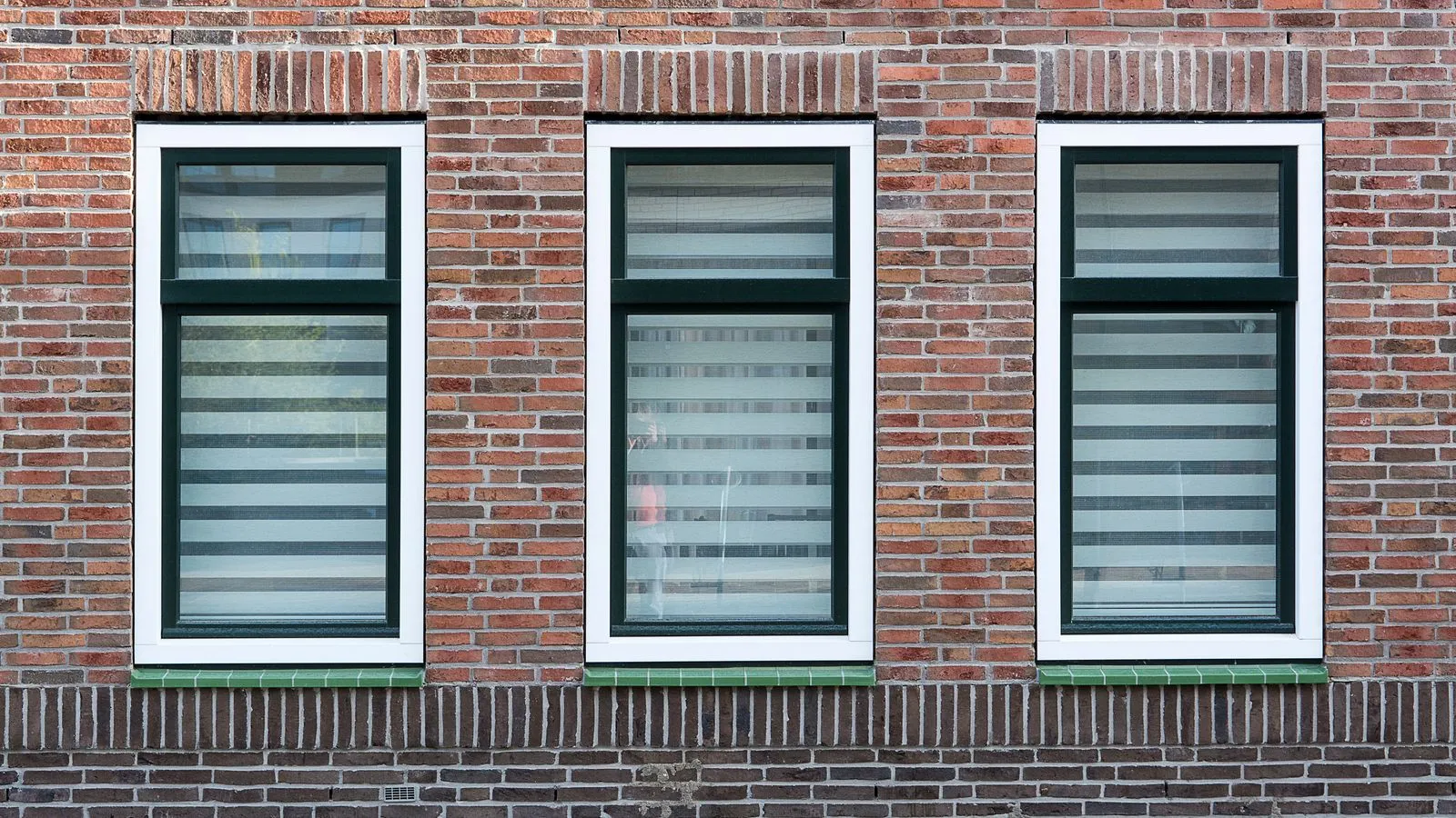 Three modern dark-framed windows in a brick wall, illustrating thermally broken window frames