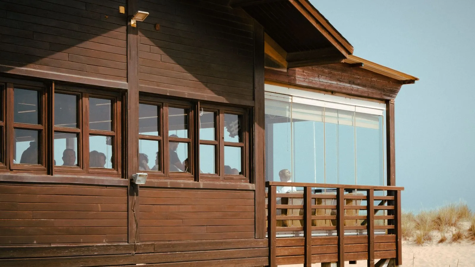 Beach house with large timber-framed windows facing the sand, showing coastal windows
